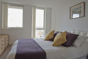 a bedroom with a bed with pillows and windows at Toothbrush Apartments - Ipswich Waterfront South - Avalon Court in Ipswich