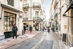 Una calle en una ciudad con gente caminando por la calle en Petit Saint Jean, en Montpellier