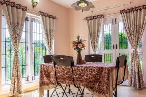 a dining room with a table and some windows at Pine View Stay Ooty in Ooty