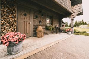 un porche de una cabaña de madera con una puerta y flores en Kalnziedi, en Sigulda