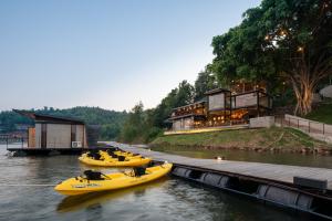 a group of yellow boats in a river with a building at Z9 Resort in Tha Kradan