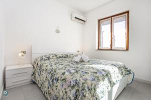 a white bedroom with a bed and a window at Villino Gramsci in San Teodoro