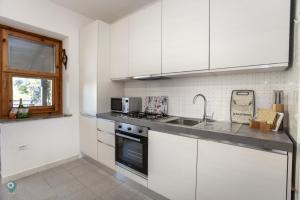a kitchen with white cabinets and a sink at Villino Gramsci in San Teodoro