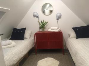 a room with two beds and a red dresser with a mirror at Beautifully Renovated Self-Contained Farm Cottage - close to beaches, North Berwick and the Golf Coast in North Berwick