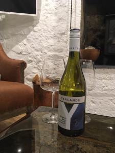 una botella de vino sentada en una mesa con copas en Beautifully Renovated Self-Contained Farm Cottage - close to beaches, North Berwick and the Golf Coast, en North Berwick