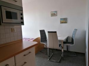 eine Küche mit einem Tisch, Stühlen und einer Mikrowelle in der Unterkunft Ferienwohnung Fröhlich in Bad Suderode