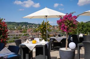 d'une terrasse avec des tables, des chaises et un parasol. dans l'établissement Hotel Banana City Winterthur, à Winterthour