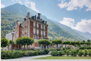 a large building with trees in front of a mountain at Résidence Regina in Cauterets