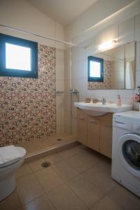 a bathroom with a toilet a sink and a washing machine at Velanidia Apartments in Plataria +119 photos