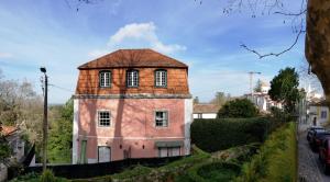 a pink house with a red roof on a street at Casa do Arco in Sintra