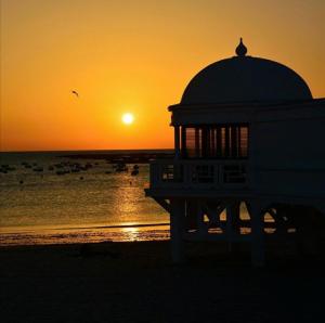 a building on the beach with the sunset in the background at Bonito piso in Puerto Real +2 photos