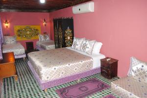 1 dormitorio con 2 camas en una habitación con paredes rosas en Riad El Bacha, en Fez