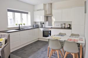 a kitchen with white cabinets and a table and chairs at Toothbrush Apartments - Central Ipswich - Fore St in Ipswich