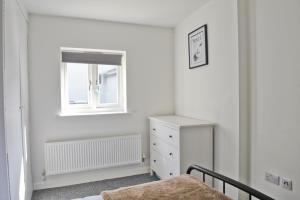 een witte slaapkamer met een bed en een raam bij Toothbrush Apartments - Central Ipswich - Fore St in Ipswich