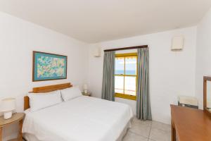 een witte slaapkamer met een bed en een raam bij Santorini - Perissa 32 in Ballito