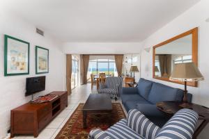 een woonkamer met een blauwe bank en een tv bij Santorini - Perissa 32 in Ballito