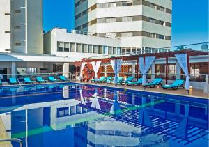 a swimming pool with blue chairs and a building at Hotel Dorado Plaza Bocagrande - All Inclusive in Cartagena de Indias