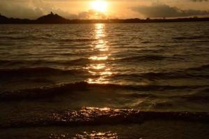 un coucher de soleil sur une étendue d'eau avec des vagues dans l'établissement Niduwari Lake Homestay, à Dambulla