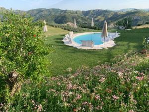 una piscina en un campo con sombrillas y flores en Residenza Case Pacifici en Ascoli Piceno