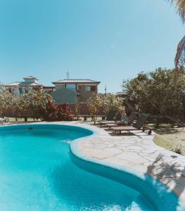 eine Frau auf einem Stuhl neben einem Pool in der Unterkunft Pousada Kailani in Búzios