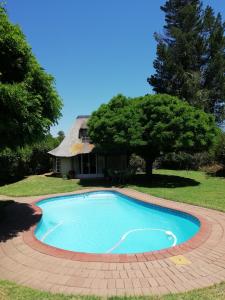 a swimming pool in front of a house at Clarens socialites, Thatch Cottage #1 in Bethlehem