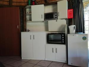 a kitchen with white cabinets and a microwave at Clarens socialites, Thatch Cottage #1 in Bethlehem