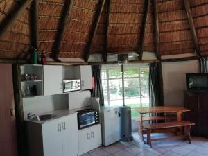 a kitchen with white cabinets and a wooden table at Clarens socialites, Thatch Cottage #1 in Bethlehem