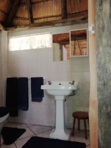 a white sink in a bathroom with blue towels at Clarens socialites, Thatch Cottage #1 in Bethlehem