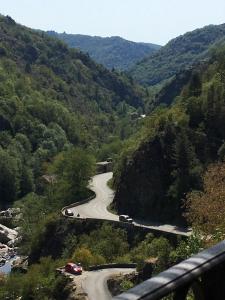 een kronkelende weg in de bergen met auto's erop bij Le Boustrophédon in Antraigues