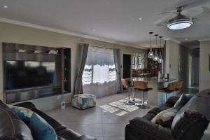 a living room with a couch and a tv and a table at C-More on Churchill in Shelly Beach