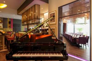 a piano in a restaurant with a bar at Steigenberger Parkhotel Braunschweig in Braunschweig