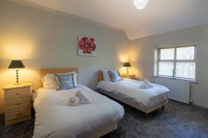 a bedroom with two beds and two lamps and a window at Graiglwyd Springs Holiday Cottages in Conwy
