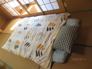 uma pequena cama num pequeno quarto com uma almofada em ゲストハウス山本 em Gifu