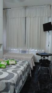 ein Hotelzimmer mit 2 Betten, einem Tisch und einem TV in der Unterkunft Apartamento Copacabana 8 in Rio de Janeiro
