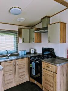 a kitchen with wooden cabinets and a stove top oven at 67 Pitgrudy Holiday Park in Dornoch