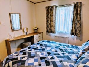 a bedroom with a bed and a mirror and a window at 67 Pitgrudy Holiday Park in Dornoch