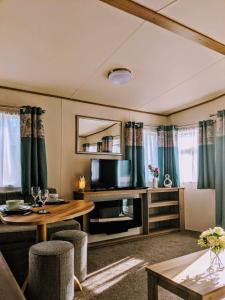 a living room with a table and a television at 67 Pitgrudy Holiday Park in Dornoch