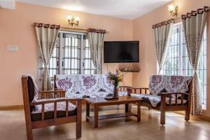 a living room with two couches and a tv at Pine View Stay Ooty in Ooty
