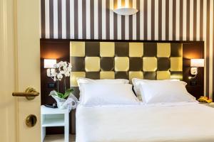 a bedroom with a white bed with a black and yellow headboard at JR Resort Logos Forte dei Marmi in Forte dei Marmi