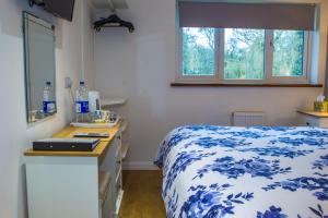 um quarto com uma cama azul e branca e um lavatório em Blyth Lodge B&B em Halesworth