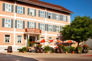 un grand bâtiment rose avec des parasols devant lui dans l'établissement Brauereigasthof Engel, à Isny im Allgäu