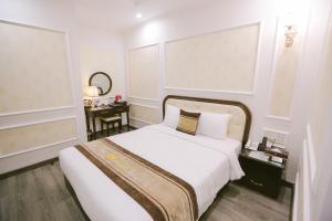 a bedroom with a large white bed and a mirror at Vincent Halong Hotel in Ha Long