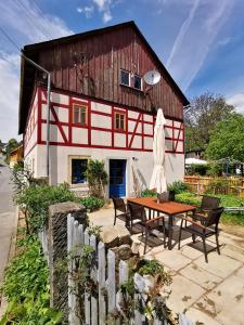 a building with a table and chairs in front of it at Urlaub im 200 Jahre alten Fachwerkhaus in Lichtenhain