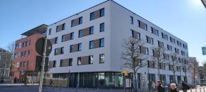 a white building on a city street with people standing outside at GINN City and Lounge Ravensburg in Ravensburg