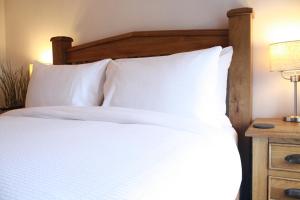 a bed with white pillows and a wooden head board at The Black Dog Inn in Dalton in Furness