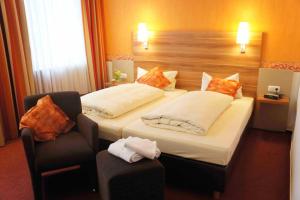 a hotel room with two beds and a chair at Hotel Café Konditorei Köppel in Bingen am Rhein