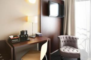 a room with a desk and a chair and a television at Logis Havvah Hôtel Gap in Gap