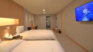 a hotel room with two beds and a flat screen tv at Mini Hotel 141 in Gyeongju