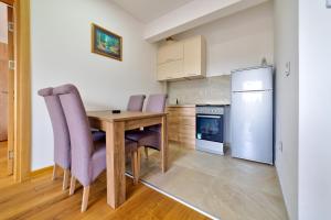 Una cocina con mesa y sillas y un refrigerador. en Apartment Victory in Vila Pekovic, en Zlatibor