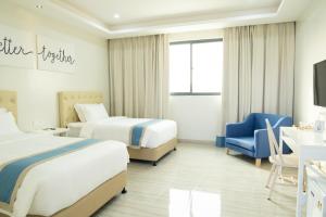 a hotel room with two beds and a blue chair at Hampton Suites in Davao City